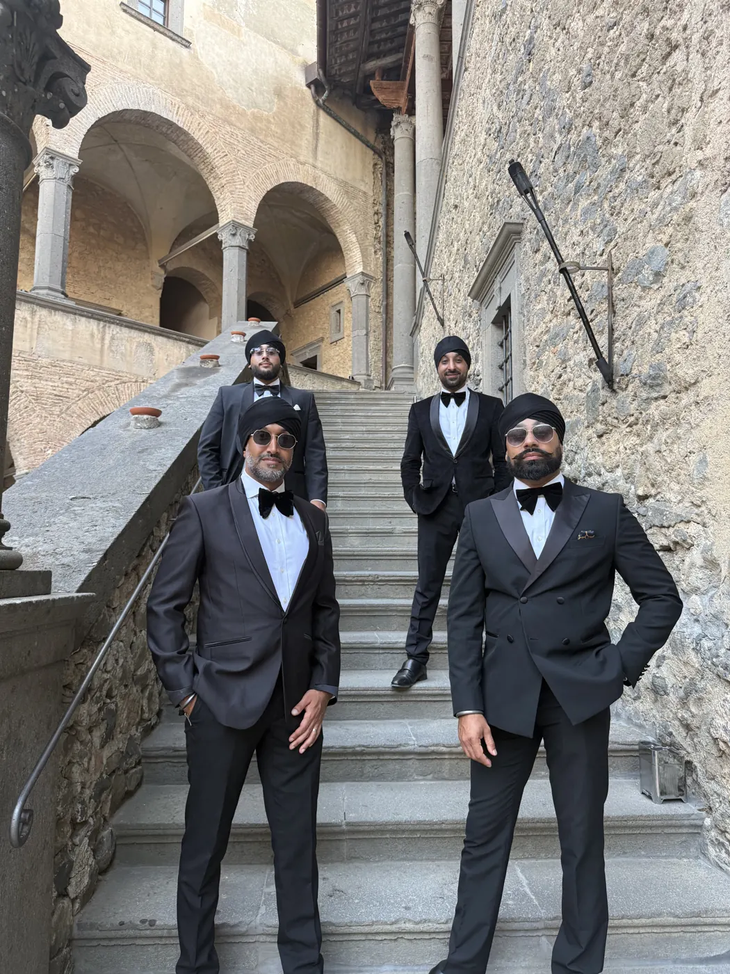 Dhol players in black dinner suits and bow ties on stone steps